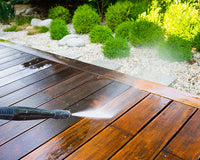 Pressure washer spraying dirt off wooden patio