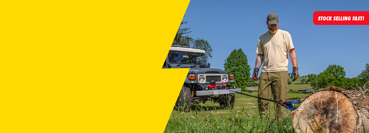 A man in outdoor work clothes stands in a grassy field next to a gray off-road vehicle, with a large bright yellow graphic block on the left side of the image and a red 'STOCK SELLING FAST!' banner in the top right.